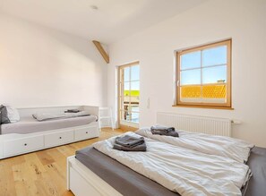 A bedroom with a bed, a sofa bed, a window, and a radiator.