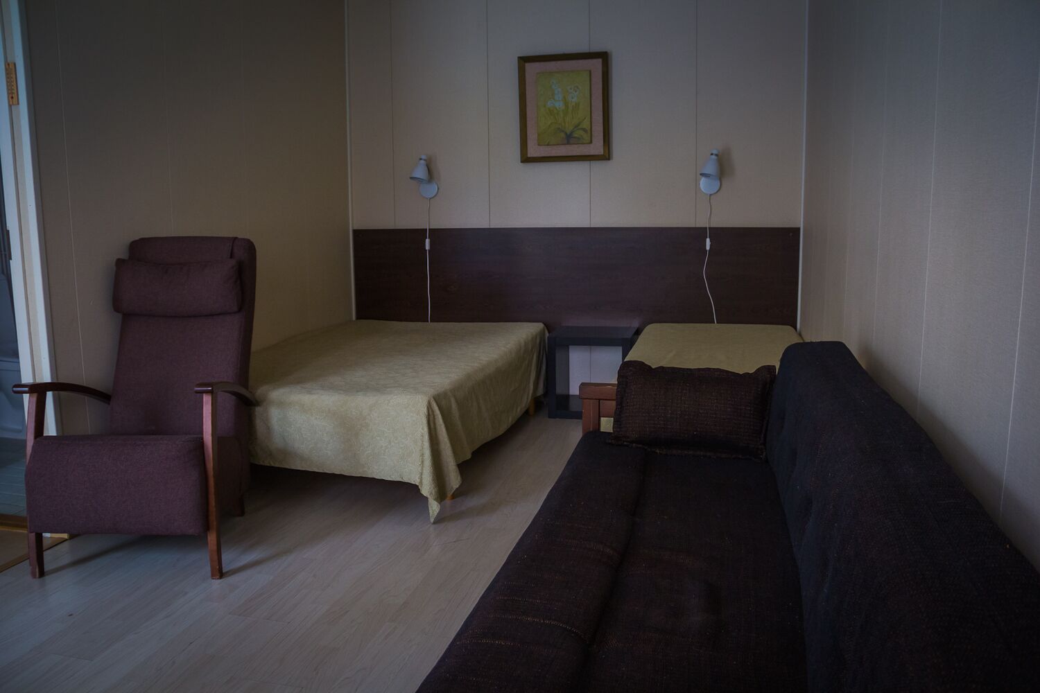 Een kamer met een bed, een stoel, een bank en twee wandlampen.