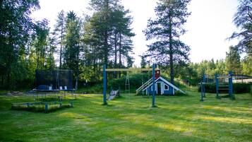 A playground with swings, slides, and a climbing structure surrounded by trees.