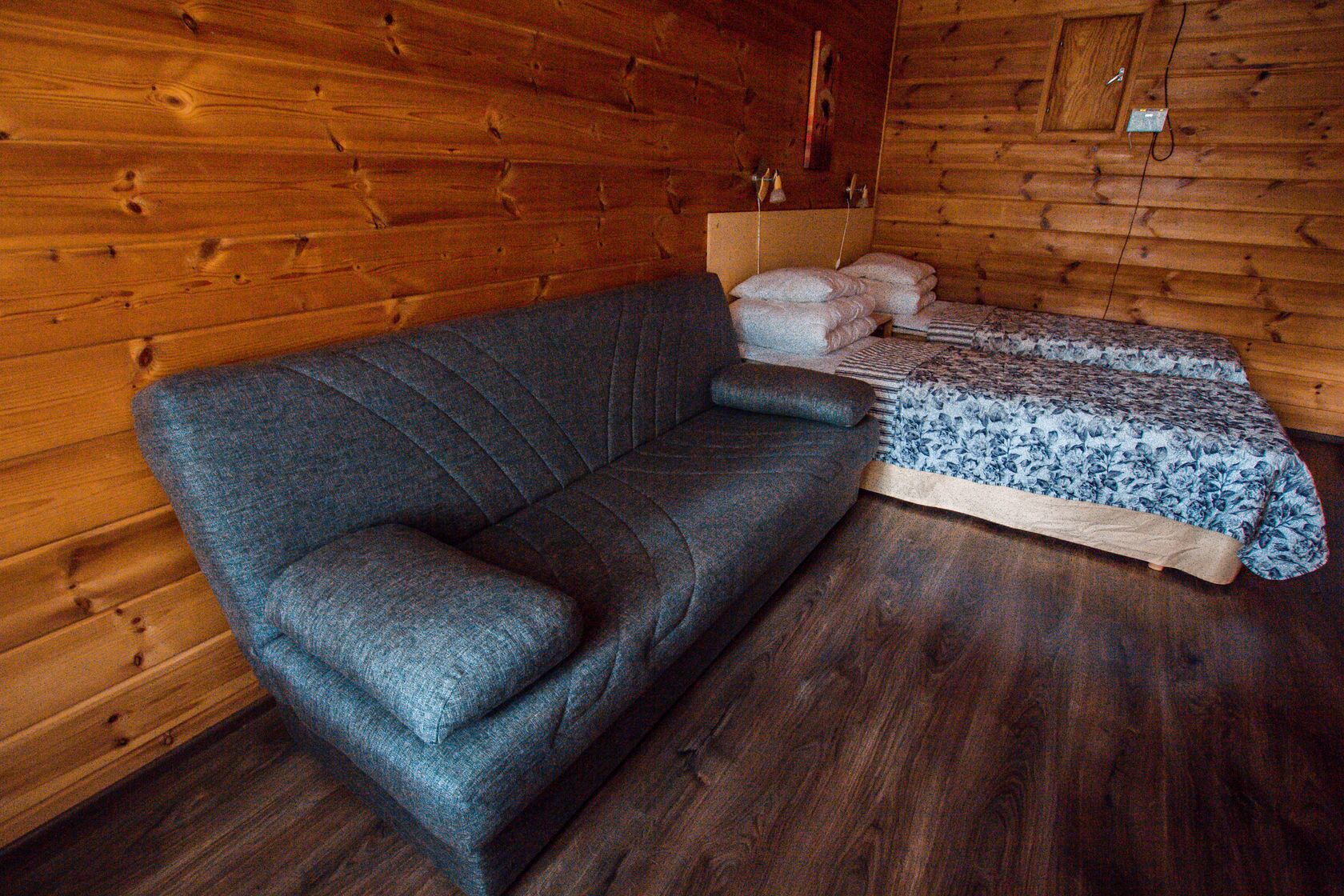 Ein Holzblockhaus-Innenraum mit einer Couch und einem Bett.
