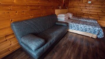 Ein Holzblockhaus-Innenraum mit einer Couch und einem Bett.