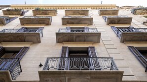 A building facade with multiple balconies, each with ornate metal railings and stone ledges. - Stylish apartment, very bright. Located in the center of Barcelona (Barcelona)