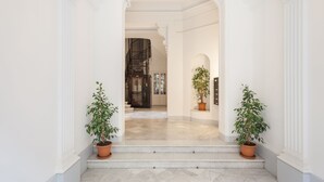A grand entrance with a marble floor, white walls, and two potted plants. - Stylish apartment, very bright. Located in the center of Barcelona (Barcelona)