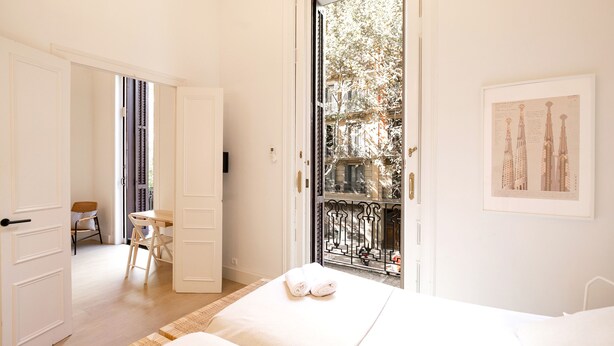 A hotel room with a bed, a desk, and a balcony with a view of buildings. - Stylish apartment, very bright. Located in the center of Barcelona (Barcelona)