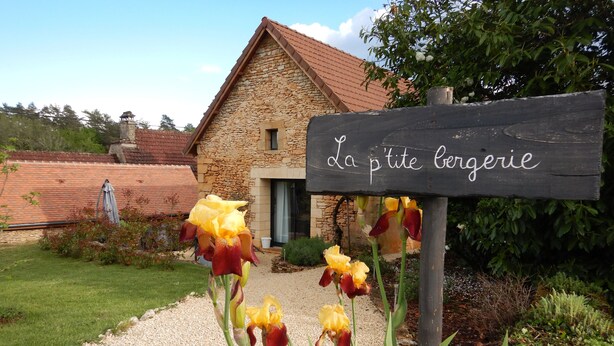 A stone building with a sign reading "La petiteagerie" surrounded by gravel and plants.