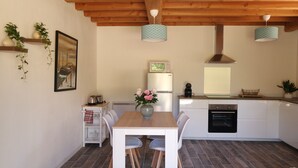 A modern kitchen with white cabinetry, a wooden dining table, and two pendant lights.