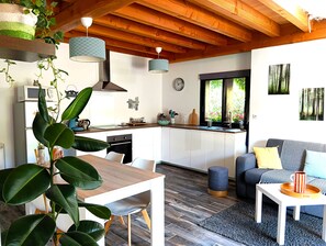 A modern kitchen with white cabinets, a wooden ceiling, and hanging pendant lights.