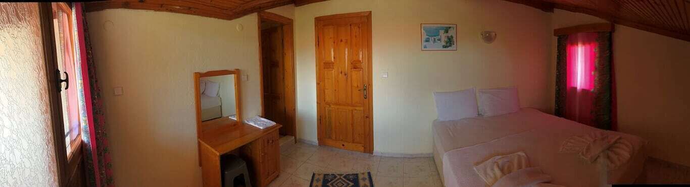 A bedroom with a wooden bed, a nightstand, a mirror, and a door leading to another room.
