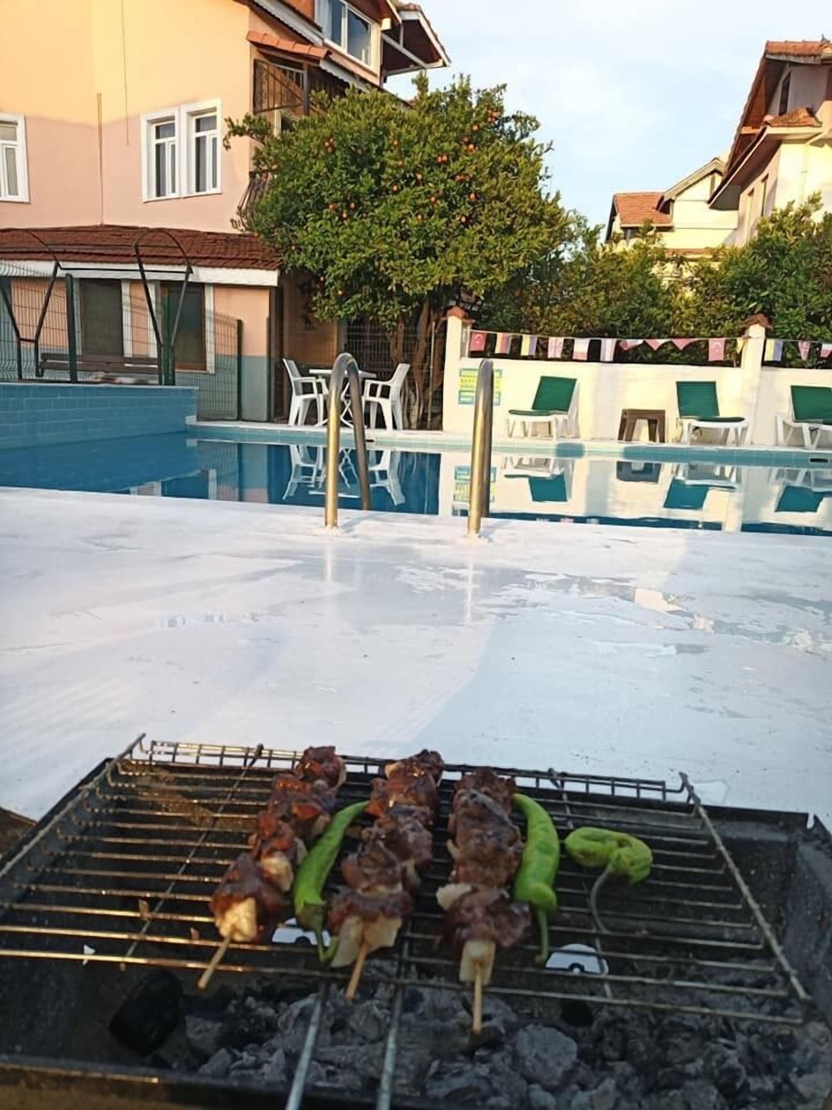 Zona de piscina exterior con una parrilla al frente.