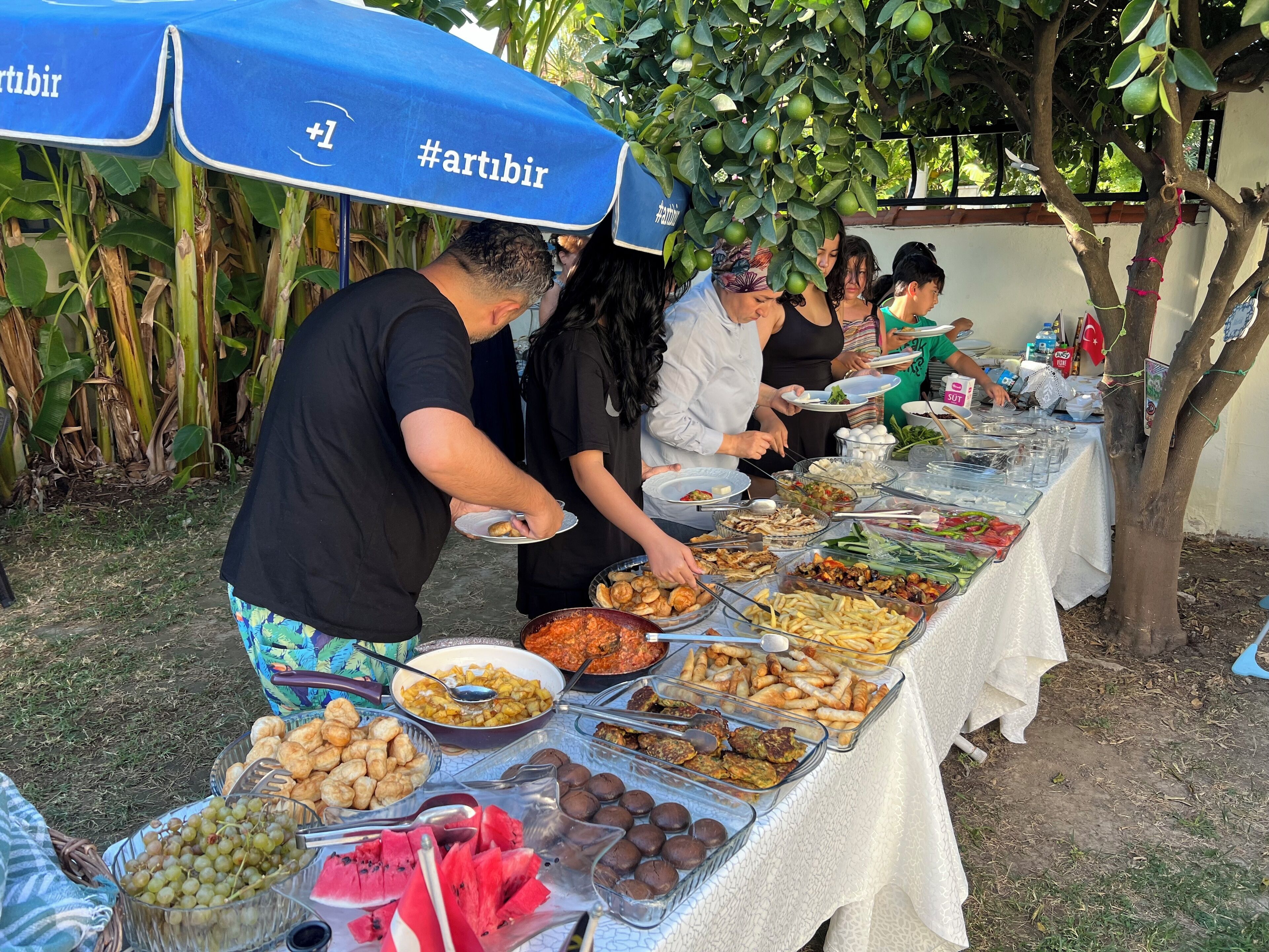 Ein reichhaltiges Buffet mit verschiedenen Speisen und Gästen, die sich bedienen.
