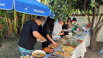 Ein reichhaltiges Buffet mit verschiedenen Speisen und Gästen, die sich bedienen.