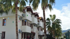 A multi-story hotel with balconies, a swimming pool, and palm trees.