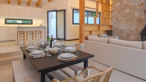 A modern kitchen with wooden beams, a stone wall, and a dining area with a table set for four. - Casa Bio Nueva: Super sea views, heated pool, 100MB wifi, A / C (Jávea)