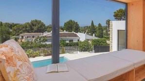 A modern room with a large window, a wooden ceiling, and a view of a swimming pool and houses. - Casa Bio Nueva: Super sea views, heated pool, 100MB wifi, A / C (Jávea)