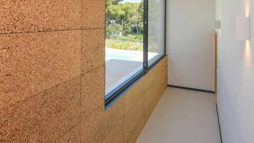 Un interior moderno con una escalera que lleva a un balcón, un ventanal grande y vistas de la vegetación al exterior.