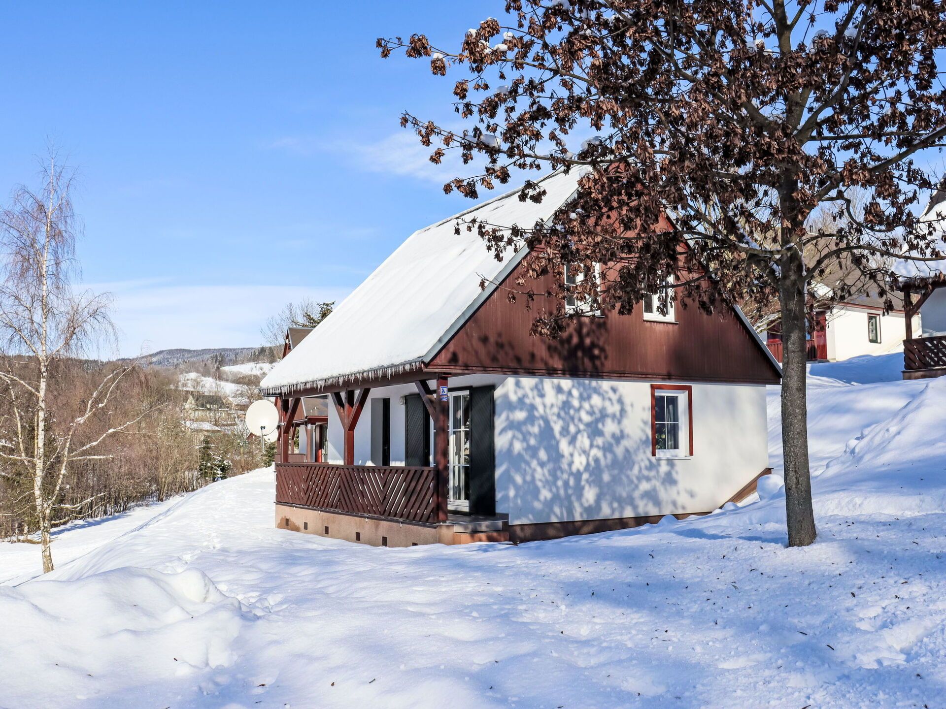 Una casa con tetto spiovente e portico in legno, immersa nella neve.