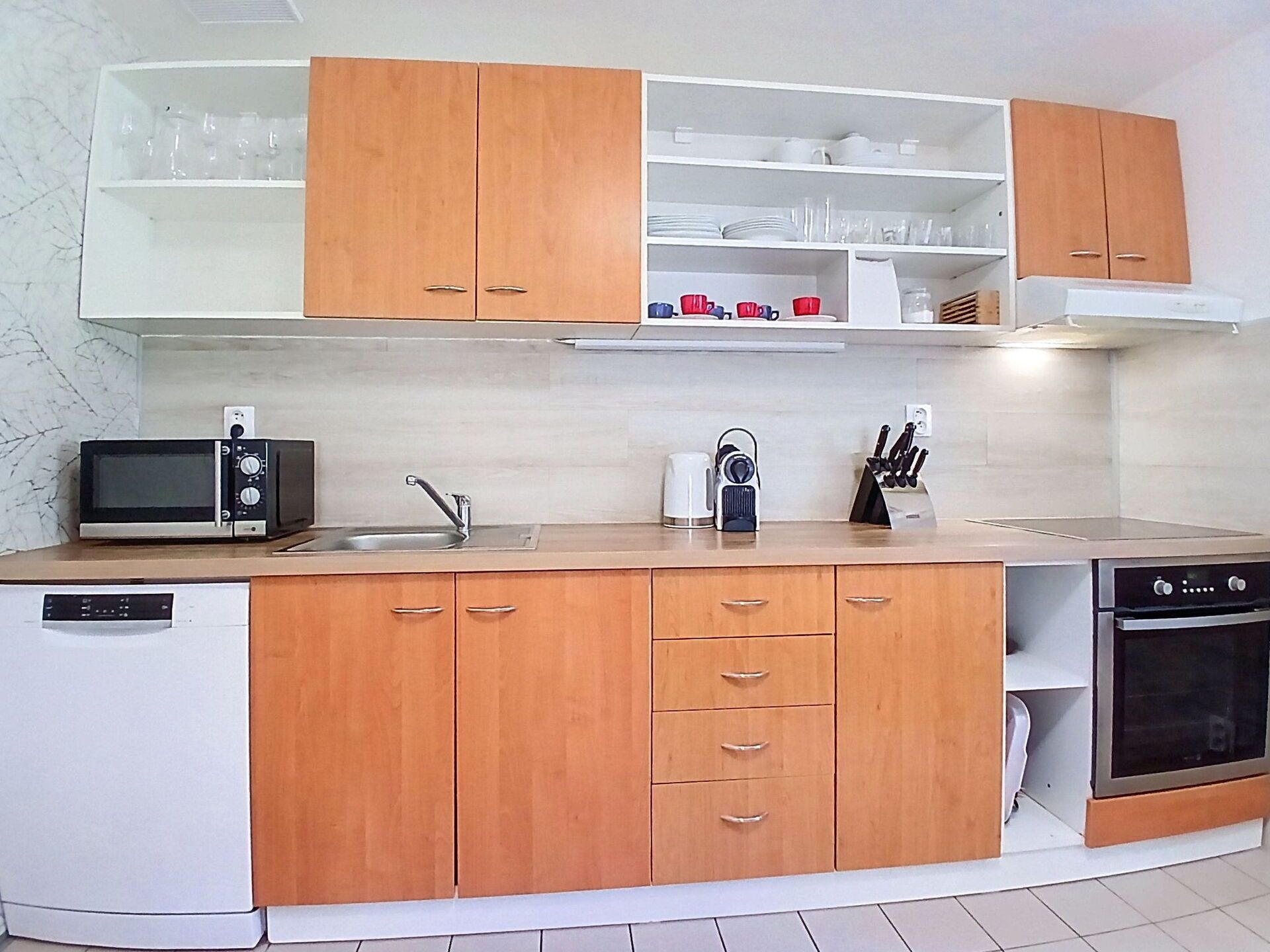 A modern kitchen with wooden cabinets, a microwave, a coffee maker, and a dishwasher.