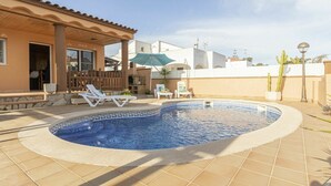 Une piscine avec des chaises longues, un patio couvert et un cactus, le tout situé dans un quartier résidentiel.