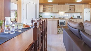 Une cuisine chaleureuse avec des meubles en bois, un coin repas avec une table et des chaises, et un canapé.