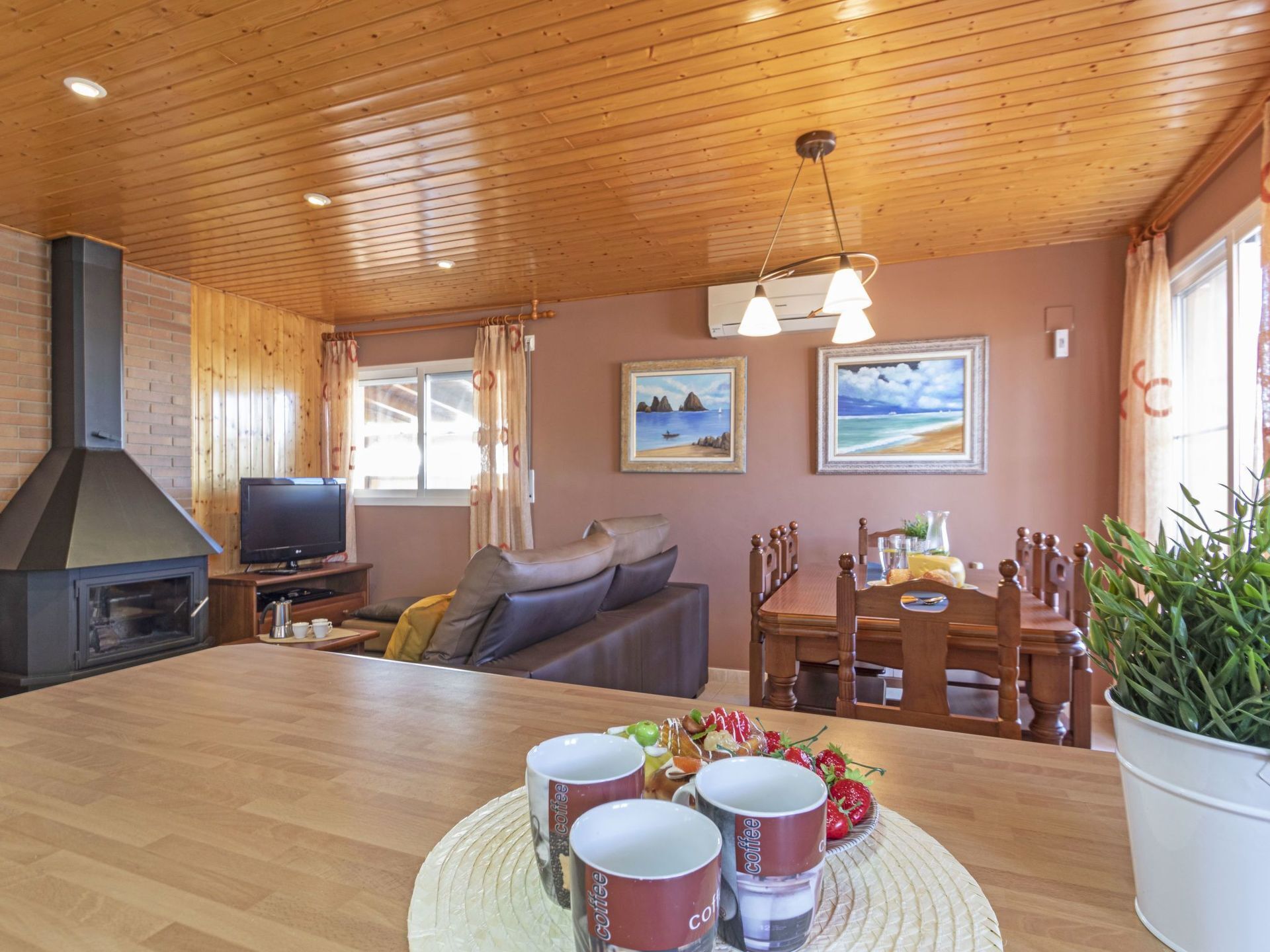 Uma sala de estar aconchegante com lareira, televisão, sofá e área de jantar com mesa e cadeiras.