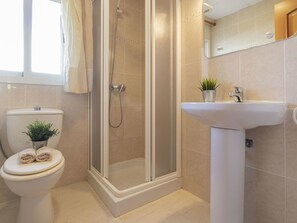 A bathroom with a toilet, a shower enclosure, and a sink.