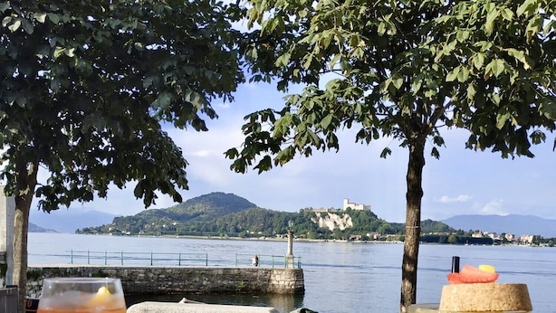 A table with food and drinks, a view of a lake, and a distant castle.