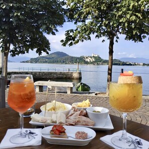 A table with food and drinks, a view of a lake, and a distant castle.