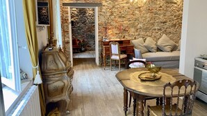 A cozy room with a stone wall, a dining table with chairs, and a sofa.