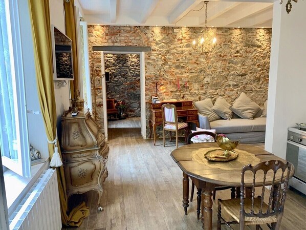 A cozy room with a stone wall, a dining table with chairs, and a sofa.