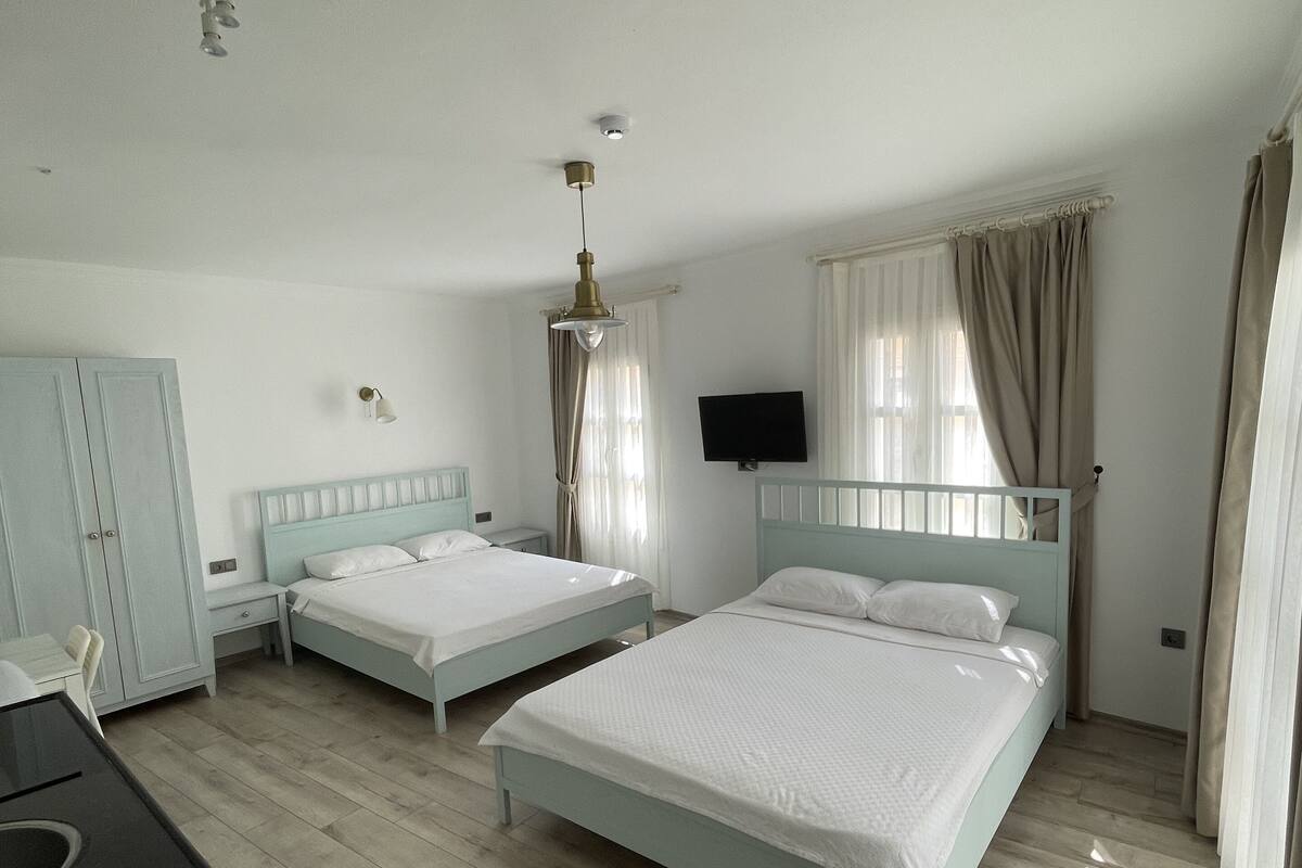 A bedroom with two beds, a desk, and a TV.