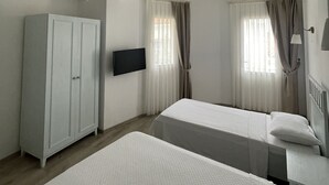 A hotel room with two beds, a wardrobe, a flat-screen TV, and a ceiling fan. - Muharrem Bey Butik Otel (Cesme)