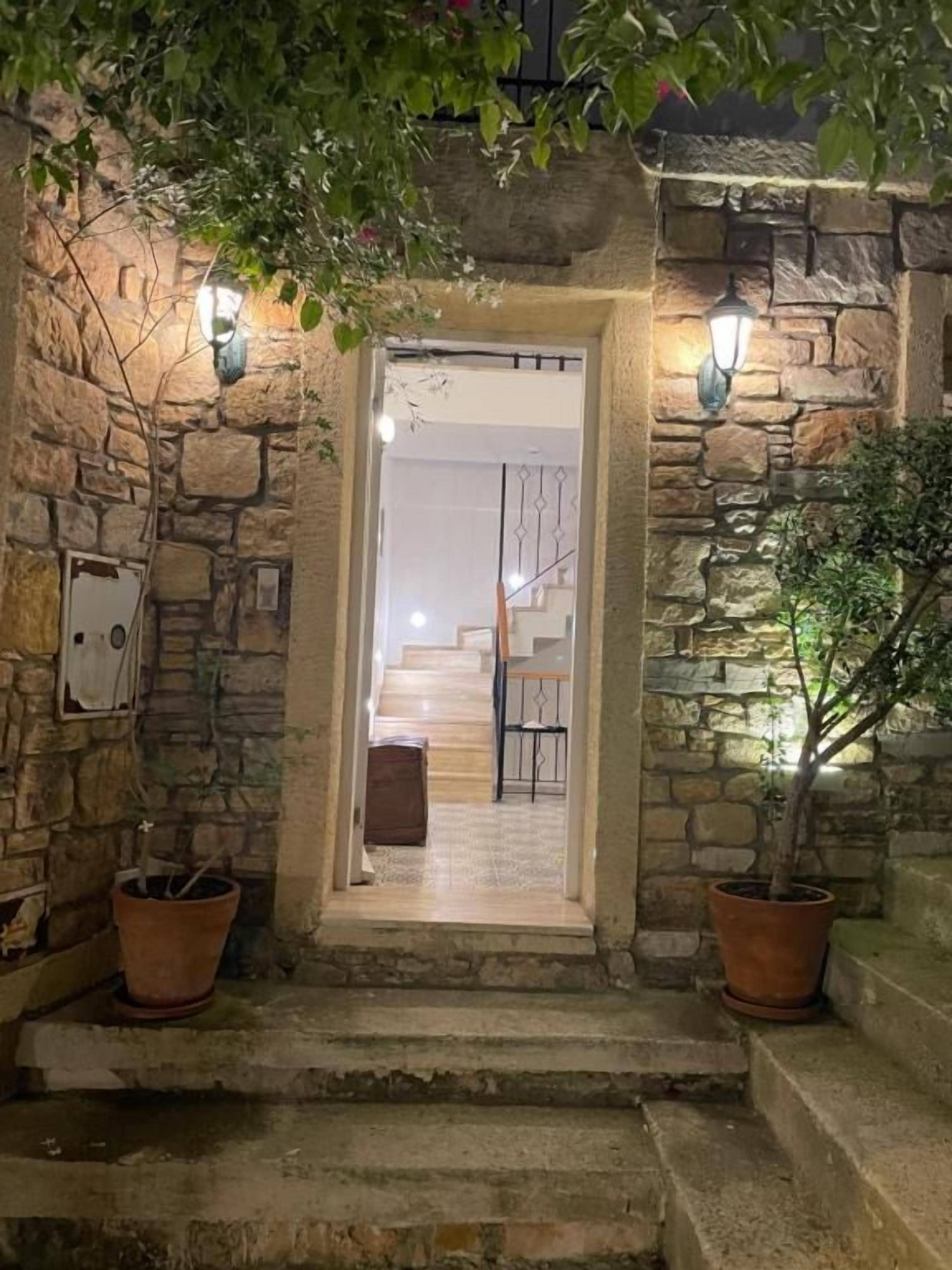 A stone entrance with steps leading to a room with a bed and a chair.