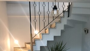 A staircase with a wooden finish, a potted plant, and patterned floor tiles. - Muharrem Bey Butik Otel (Cesme)