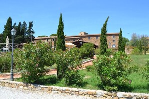 Experience the charm of a traditional Mediterranean-style courtyard with a central stone wall and lush greenery.
