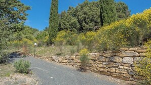 A stone wall with a gravel path leading to a stone building. - Villa for groups and families, with Private Pool in Monteverdi Marittimo (Monteverdi Marittimo)