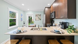 Cozinha moderna com ilha central, banquetas e vista para o jardim pela janela.