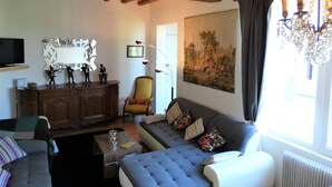 A living room with a sofa, armchair, wooden cabinet, and a television. - Splendid view of the Château and the Loire (Saumur)