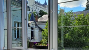 A bedroom with a large window overlooking a castle and greenery. - Splendid view of the Château and the Loire (Saumur)