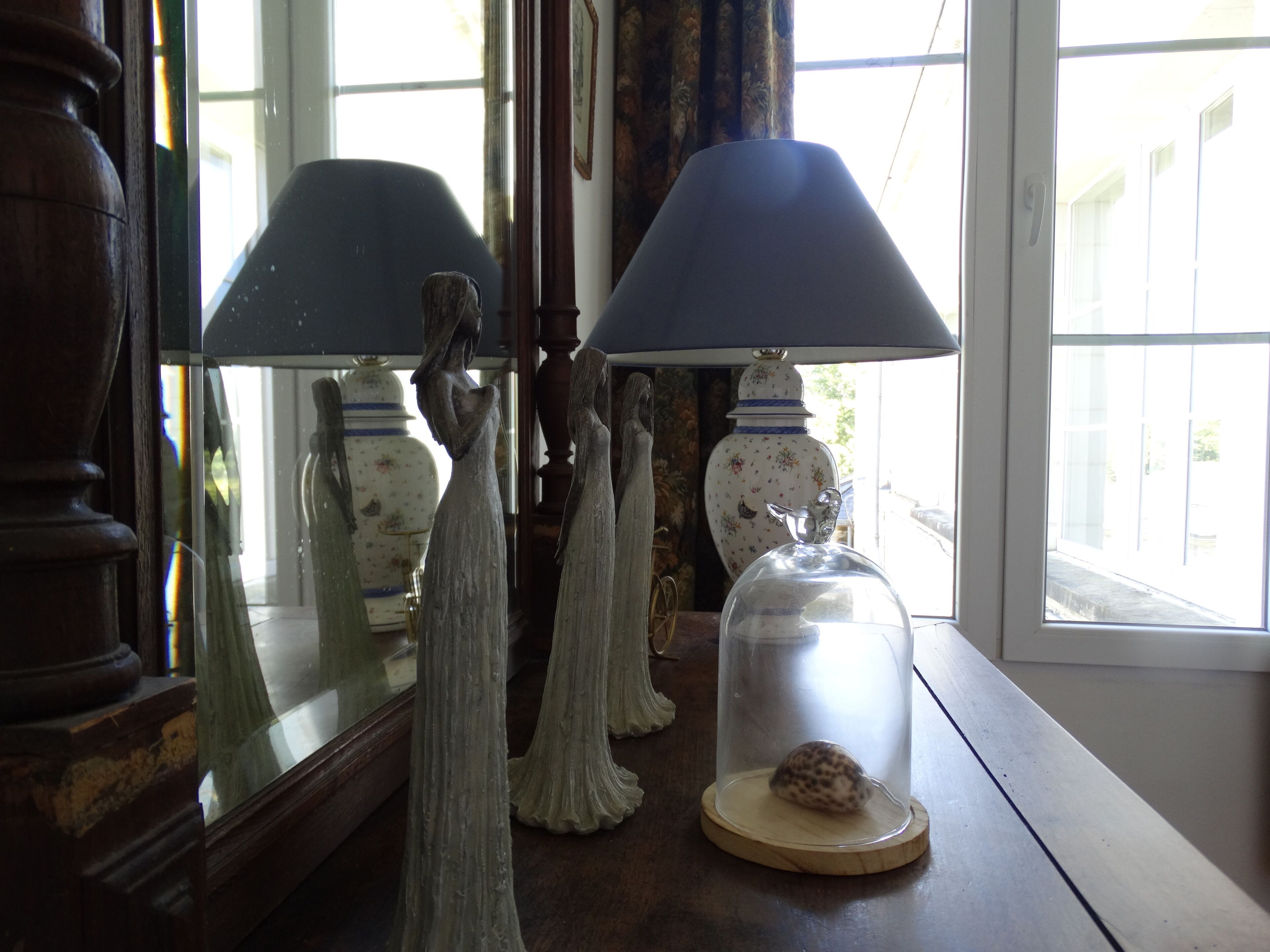 Ein Tisch mit zwei Lampen, einer Glasglocke mit Schnecke und einer dekorativen Vase.