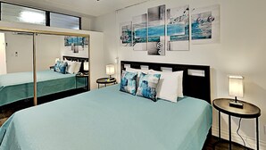 Een hotelkamer met een groot bed, een grote spiegel, een nachtkastje met een lamp en kunst aan de muur.