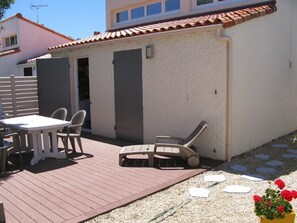 Enjoy a patio with a table, four chairs, and a lounge chair, surrounded by lush greenery and a tiled roof.