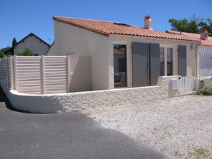 A simple, single-story building with a sloped roof and flat overhang, featuring a door and windows.