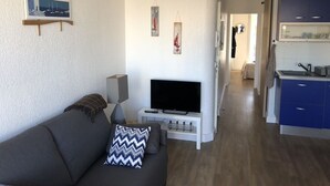 A modern living room with a sofa, a flat-screen TV, and artwork on the wall. - T2 comfortable Marina de Canet Plage (Canet-en-Roussillon)
