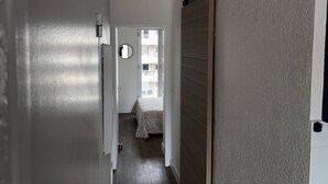 A hallway with a sliding door leading to a bedroom with a bed and a window. - T2 comfortable Marina de Canet Plage (Canet-en-Roussillon)