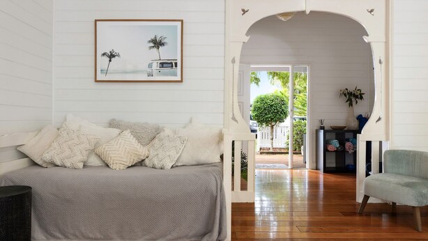 A cozy room with a bed, a framed picture of a van on the wall, and a view of a garden through an open doorway. - Aaloka Bay - heritage charm w. pool & spa (Byron Bay)