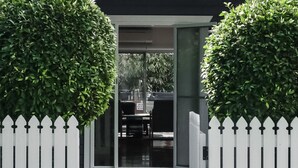 A gated entrance with a white picket fence and trimmed hedges. - Aaloka Bay - heritage charm w. pool & spa (Byron Bay)
