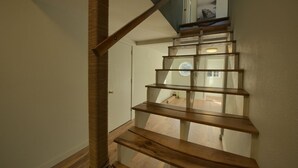 Eine Holztreppe mit Glastrennwand, die zu einer Empore führt.