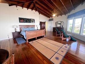 A bedroom with a wooden bed, a futon, a large window, and a tatami mat.