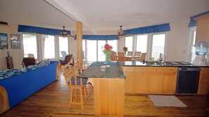 Een ruime keuken met houten kasten, een centraal eiland en een eetgedeelte met stoelen.