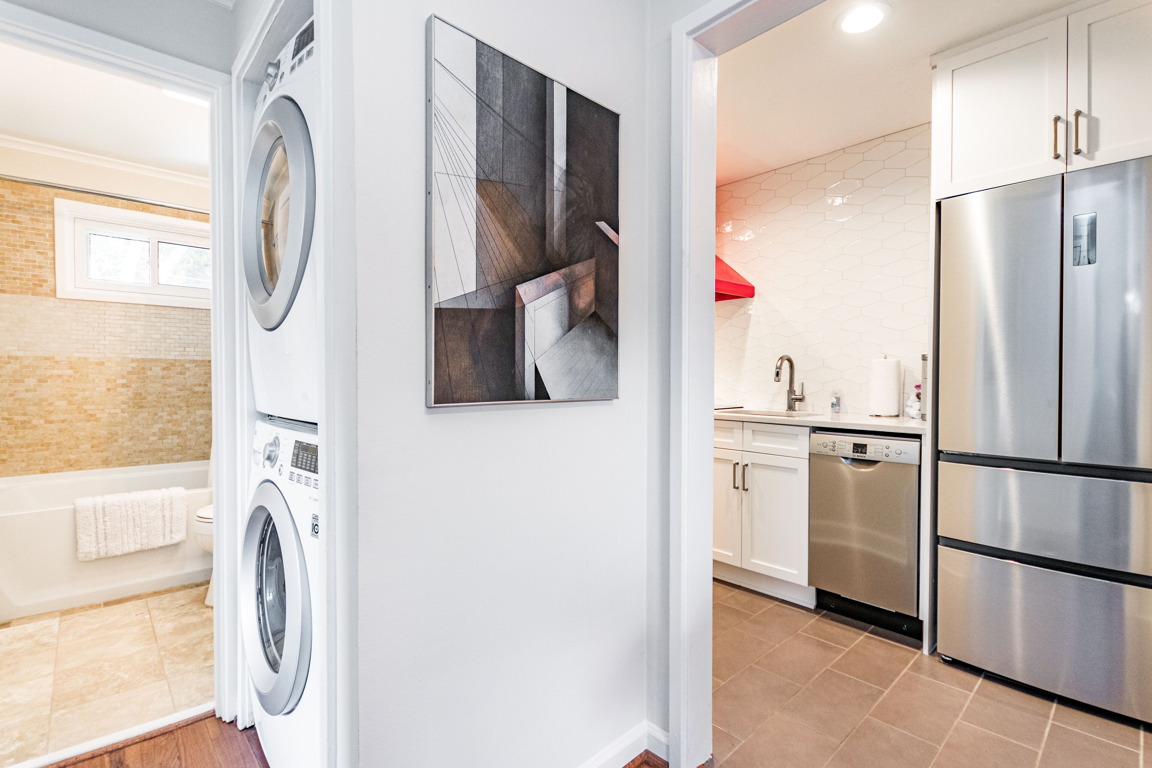 A modern kitchen with stainless steel appliances, a dishwasher, and a red accent wall.